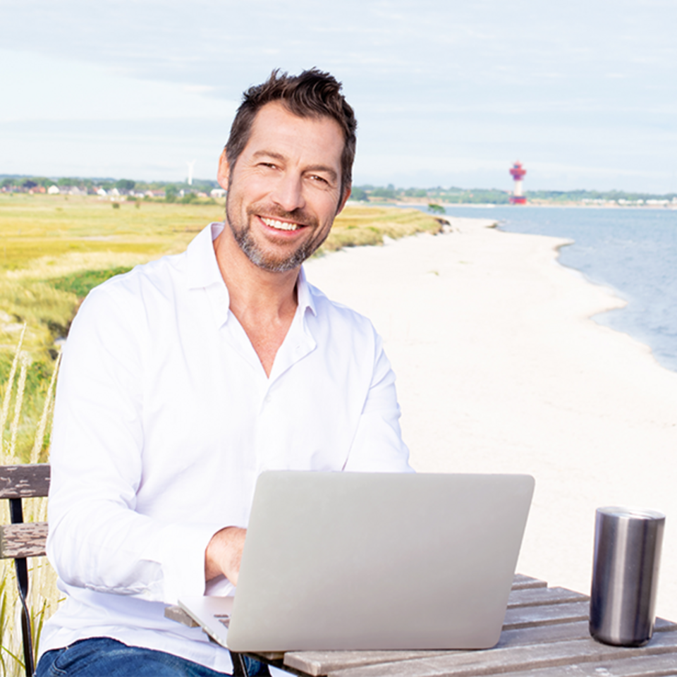 Mann mit Laptop an norddeutscher Küste
